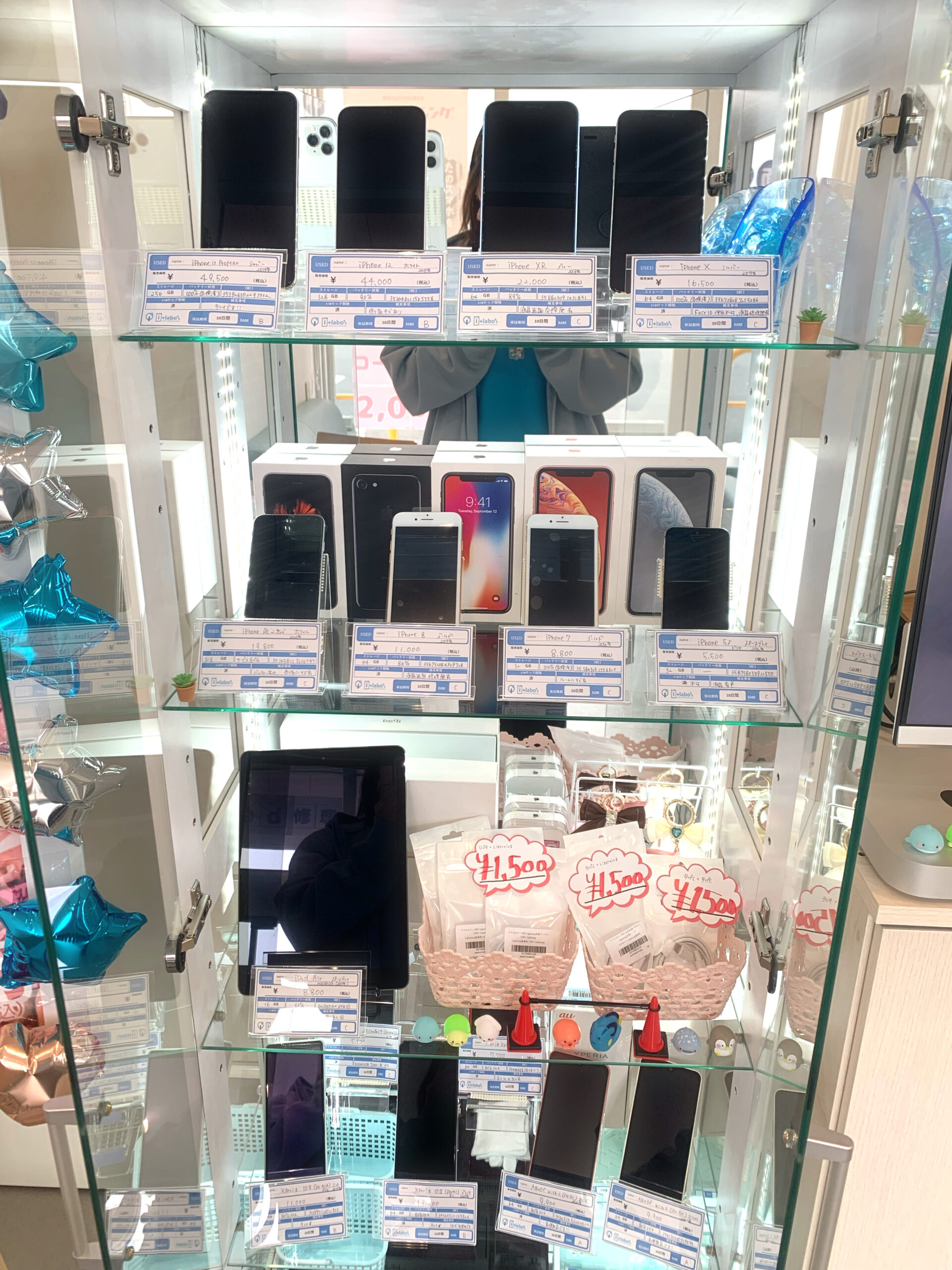 中古スマホと中古iPhoneが店頭にずらりと並んでいる様子（i+labo足利福居ショッピングセンター店）